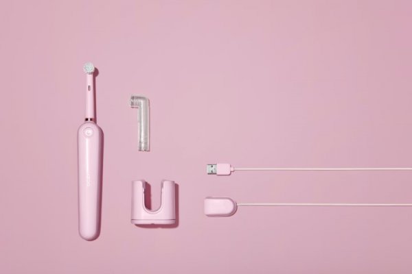 Pink electric toothbrush with charging base and cable